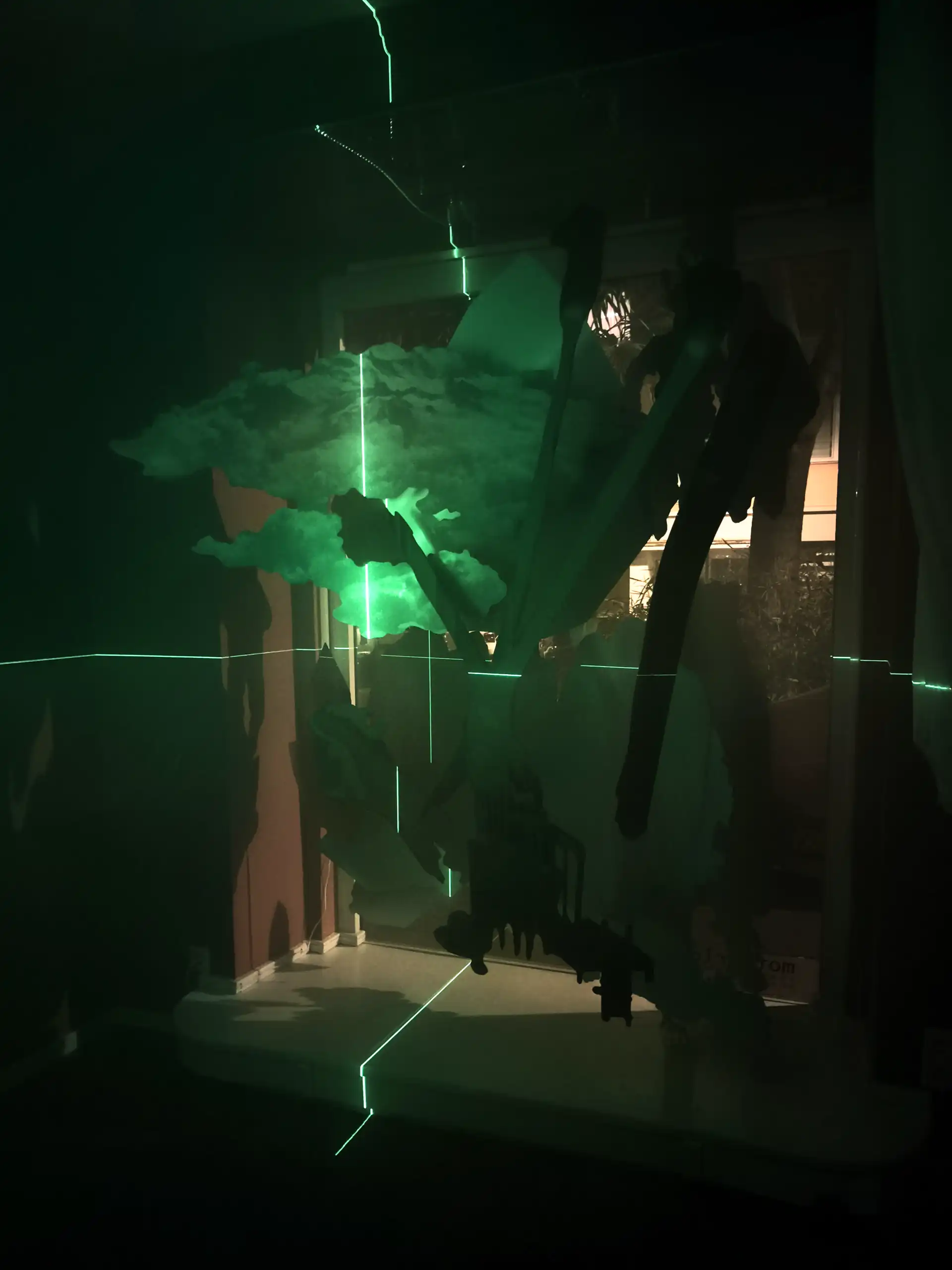 Grüne Laser malt ein Fadenkreuz auf die Skulptur eines Baums