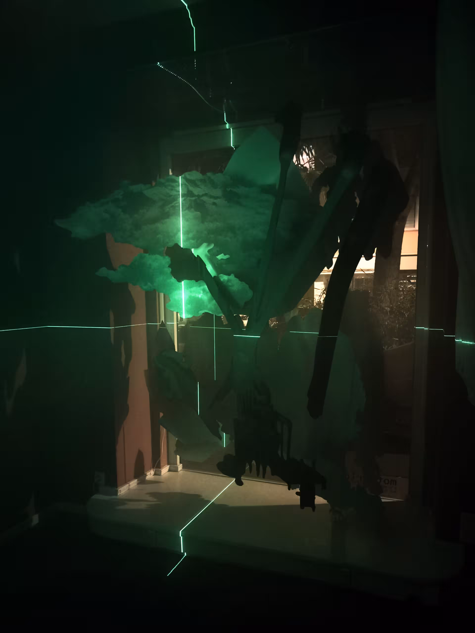 Grüne Laser malt ein Fadenkreuz auf die Skulptur eines Baums